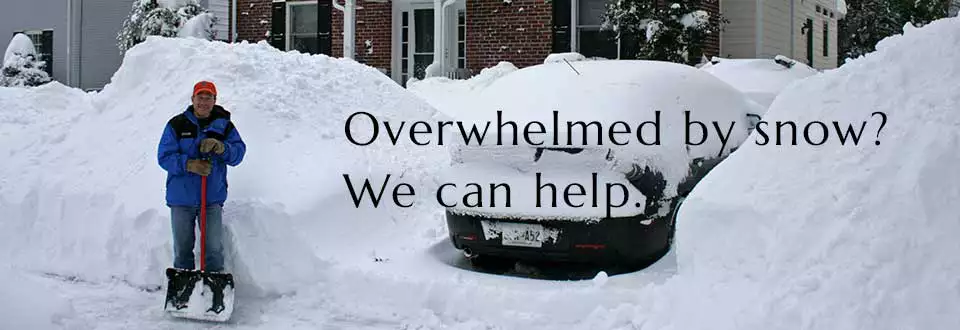 A man is holding a shovel while he is standing next to his car that is parked in his dive-way. But the car is covered in snow, so he can't get to work in time.