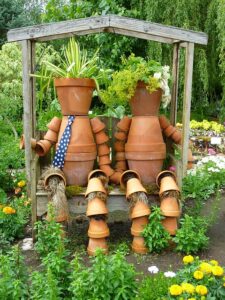 Photo of clay flower pots stacked to look like a couple sitting on a garden bench.